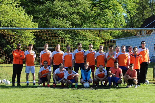 Die Fußballmannschaft des Berufsbildungswerks Neckargemünd in den orangenen Trickots vor einem Fußballtor.