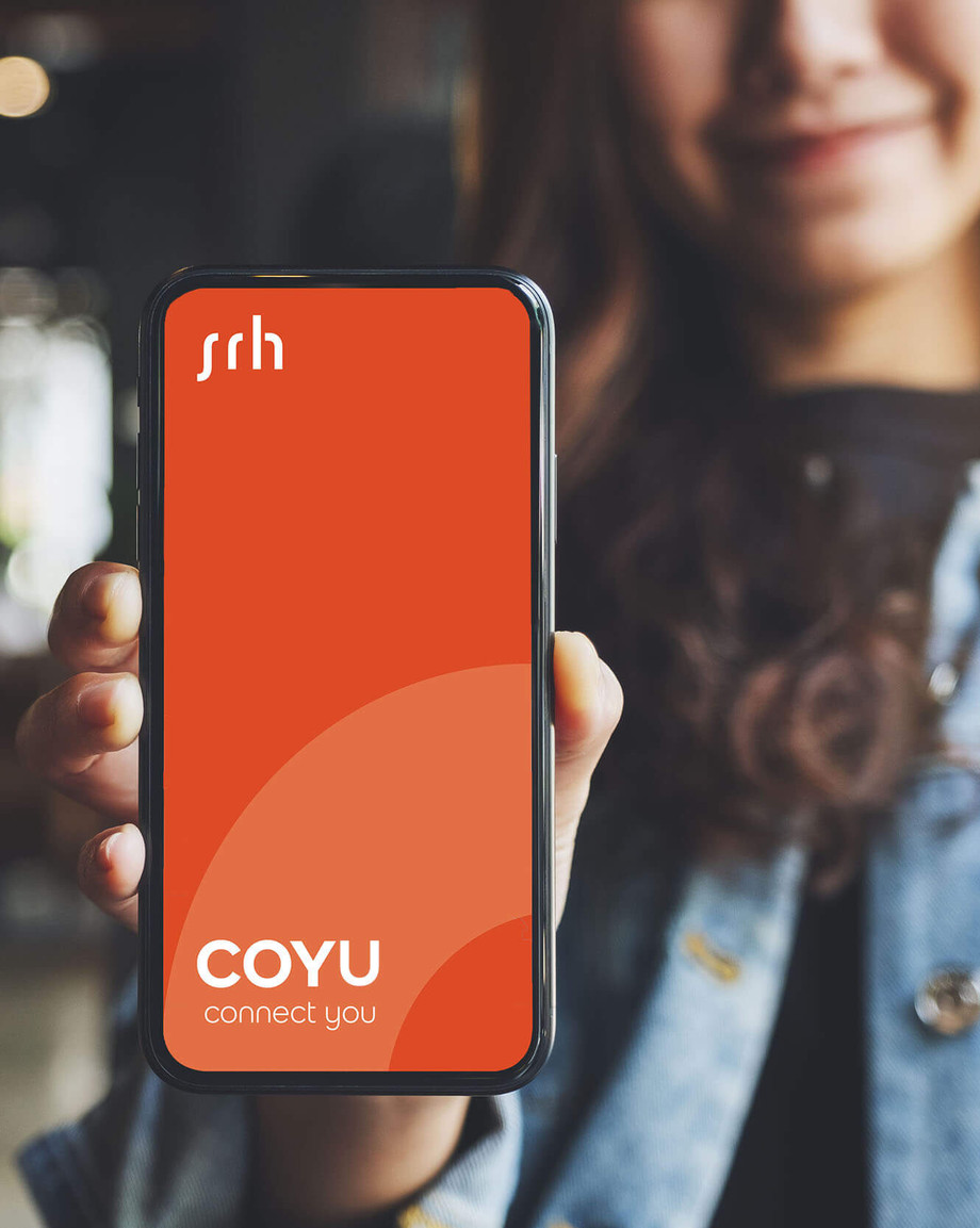 Junge Frau hält Hand ins Bild mit der Campus App COYU des SRH Berufsbildungswerks Neckargemünd