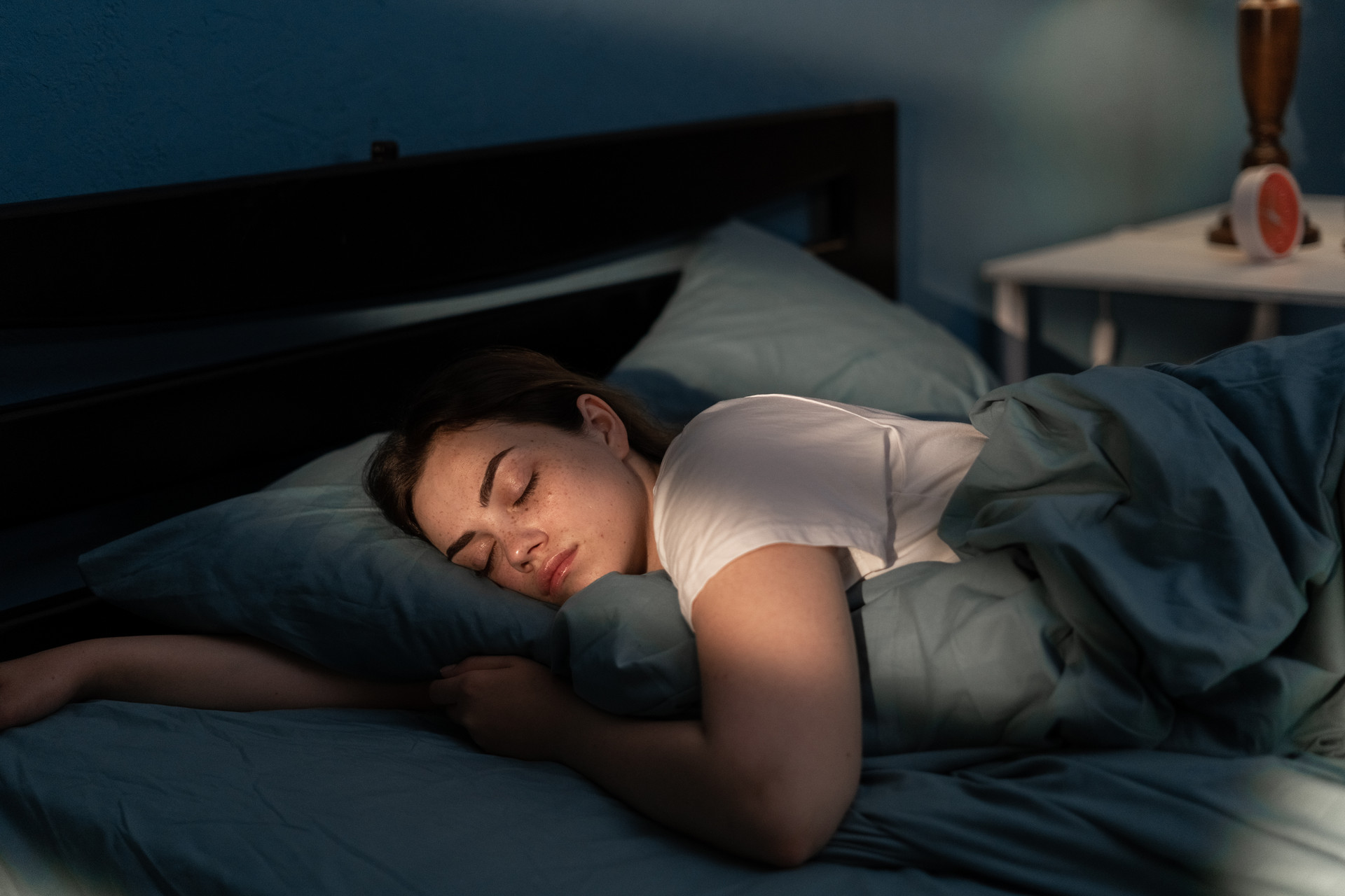 Eine Person schläft auf einem Bett in einem dunklen Raum.