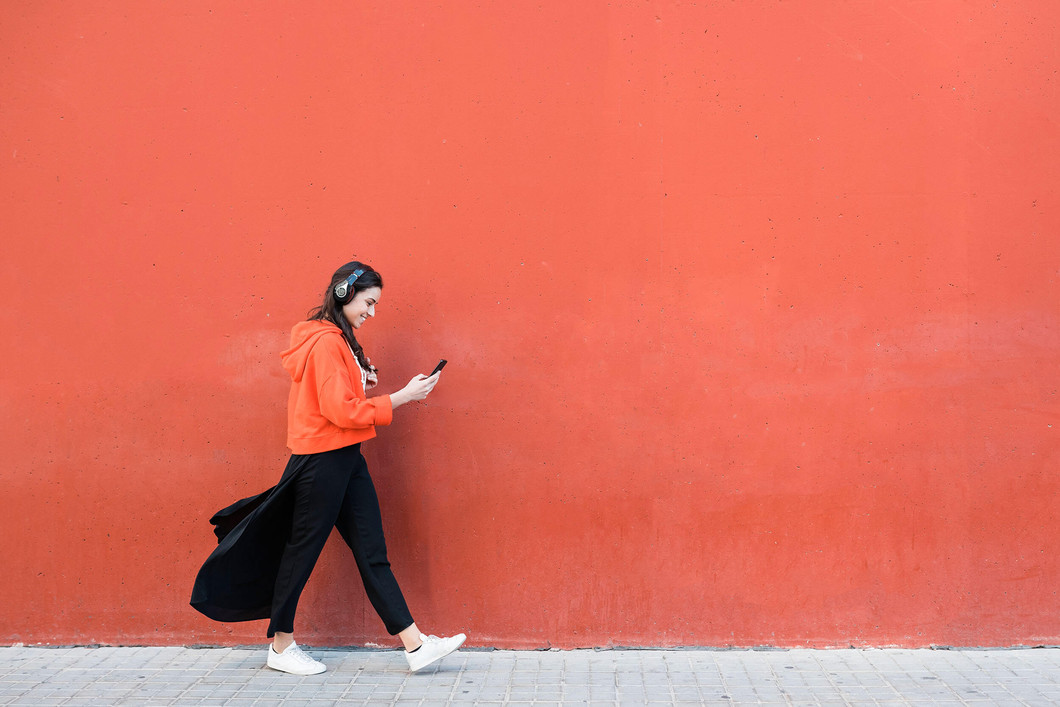 Junge Frau läuft an einer Wand des SRH Berufsbildungswerks Neckargemünd und schaut dabei auf ihr Smartphone